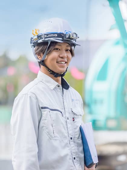 施工管理の男性スタッフ。ヘルメット姿で書類を持っている。